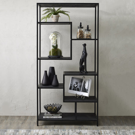 Hill Interiors large black metal multi-shelf storage unit styled with a fern, orchid dome, black vases, figurine and books against a pale wall.