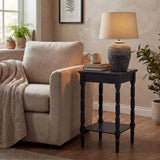 Hill Interiors Ferranock carved stone-effect ceramic table lamp in beige with tapered shade, styled on a black side table beside a linen armchair.