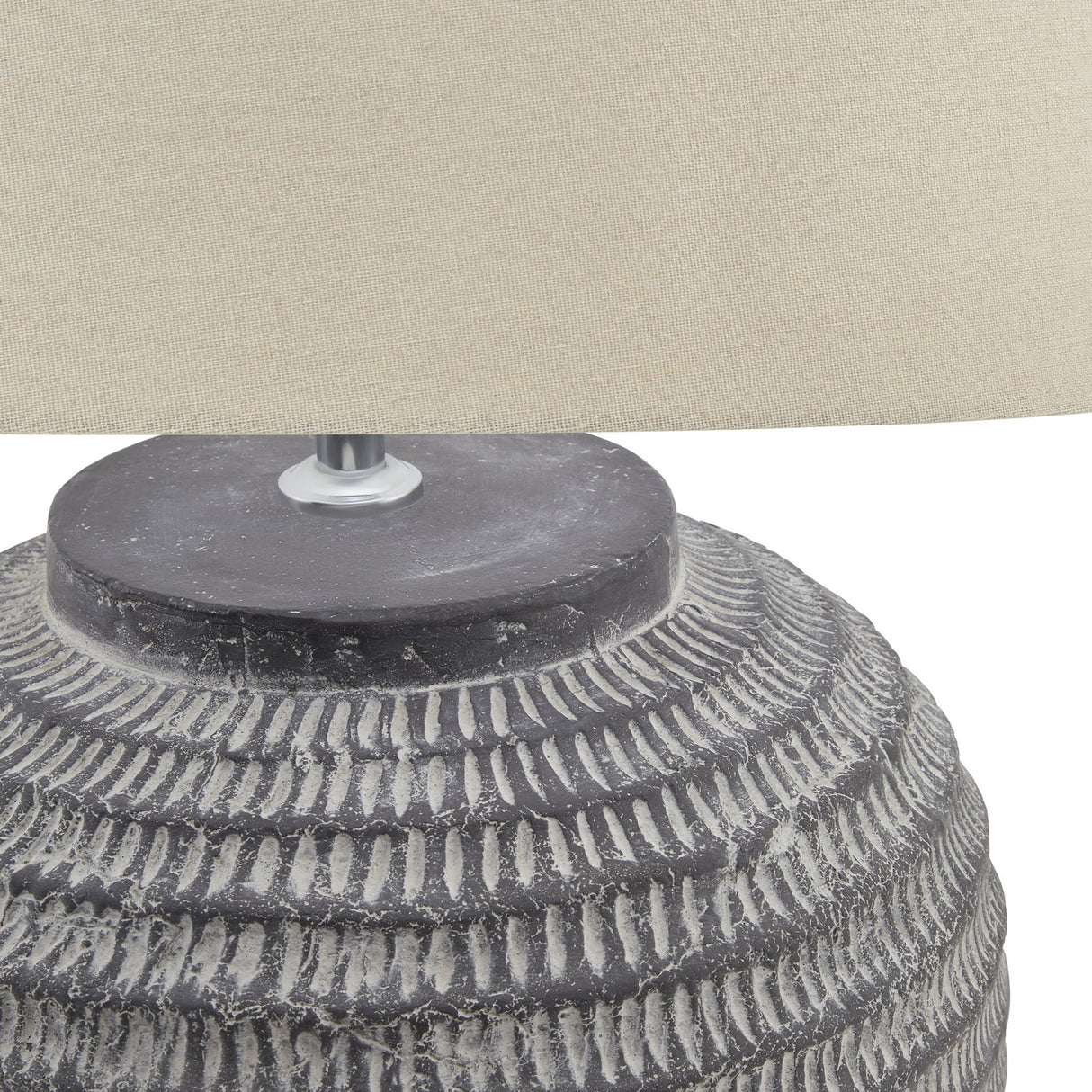 Close-up of Hill Interiors Ferranock ceramic table lamp showing carved stone-effect grey base detailing beneath a beige linen shade.