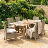 Hill Interiors beige powder-coated metal outdoor dining chairs set around a wooden garden table with wine and pizza on a sunny patio.
