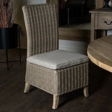 Hill Interiors woven high-back dining chair in beige with a linen seat cushion and wooden legs, placed beside a round timber table and mirror.
