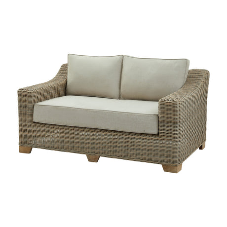 Hill Interiors Rattan Two-Seater Garden Sofa in beige, with woven rattan frame, sloped arms, wooden feet and plush cushions on a white background.