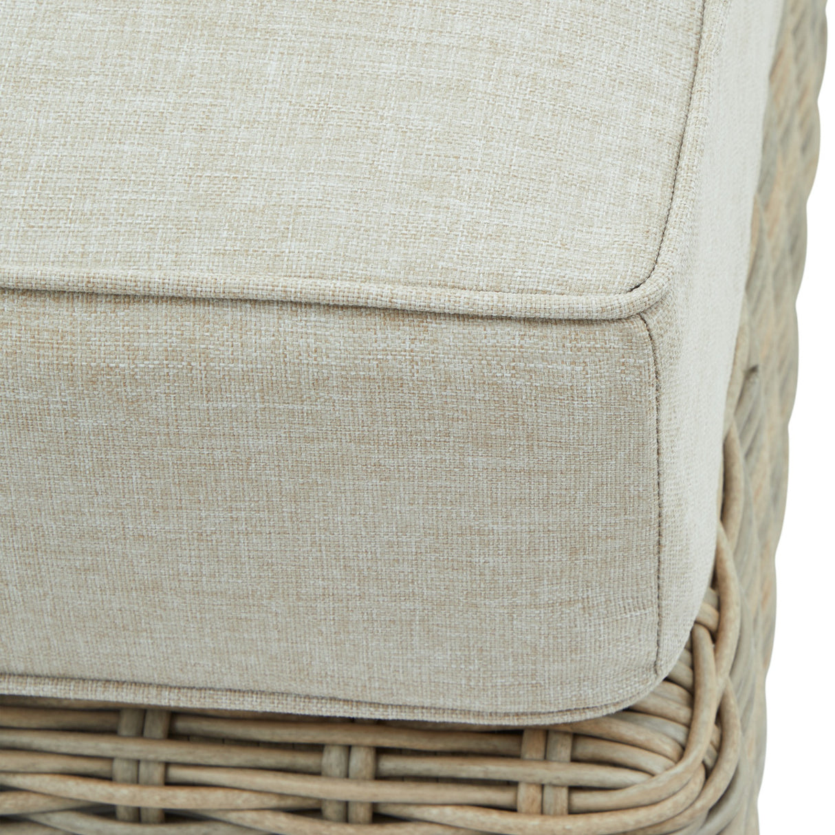 Close-up of Hill Interiors Outdoor Foot Stool showing the beige woven cushion top with piped edging and pale rattan-style base.