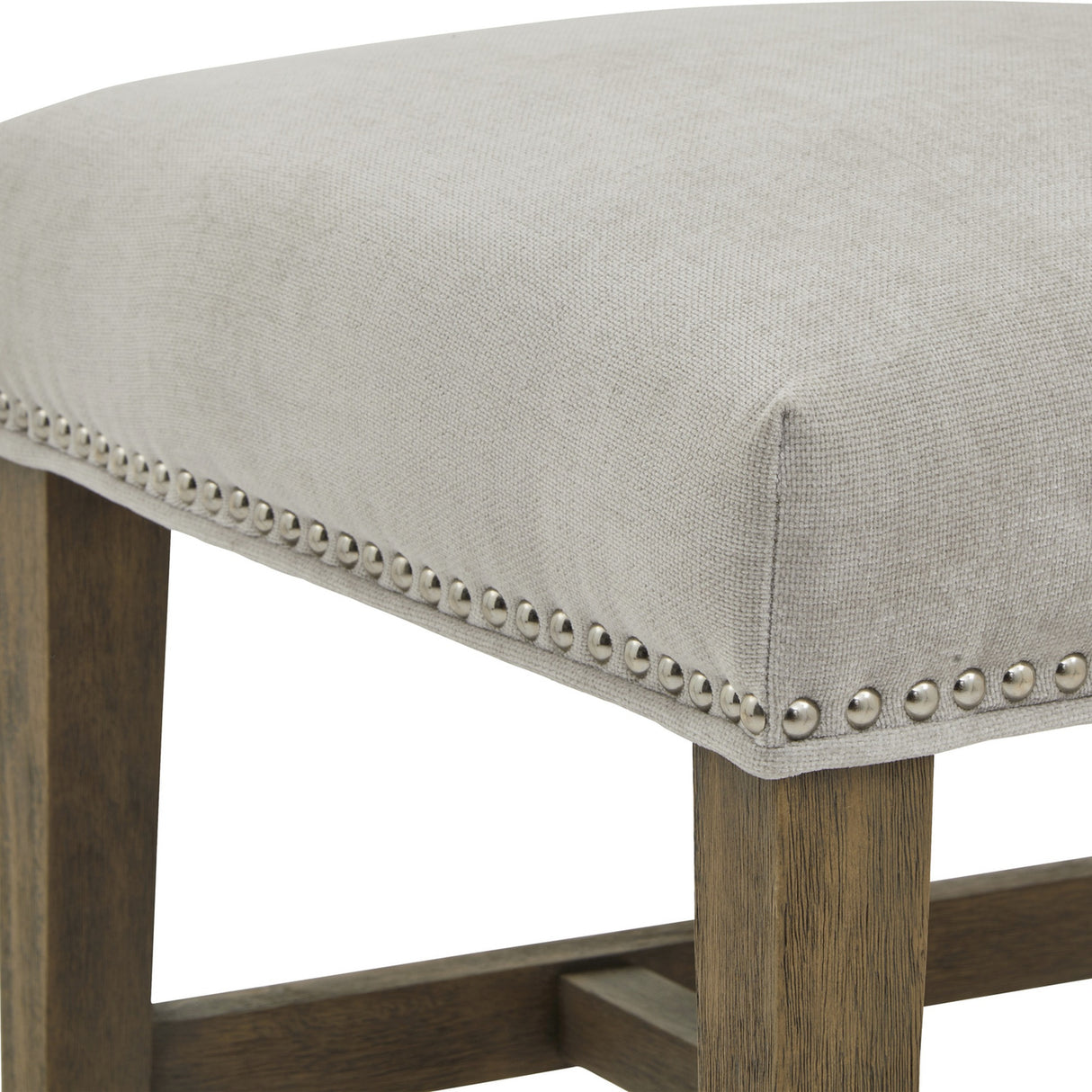 Close-up of the Hill Interiors Grey Wooden Dining Chair showing the light grey upholstered seat with silver nailhead trim and wooden legs.