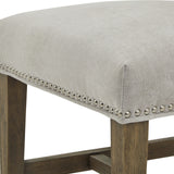 Close-up of the Hill Interiors Grey Wooden Dining Chair showing the light grey upholstered seat with silver nailhead trim and wooden legs.