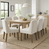 Hill Interiors Braxdon cream bouclé dining chairs set around a pale oak table in a bright dining room with jute rug and dome pendant light.