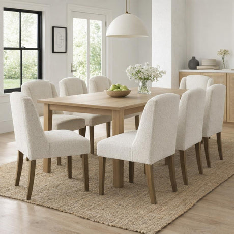 Hill Interiors Braxdon cream bouclé dining chairs set around a pale oak table in a bright dining room with jute rug and dome pendant light.