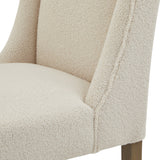 Close-up of the Hill Interiors Braxdon cream bouclé dining chair showing the looped textured upholstery on the curved back, armrest and seat.