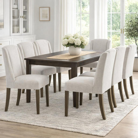 Hill Interiors Braxdon grey upholstered dining chairs with dark wood legs set around a dark wood table in a bright neutral dining room.