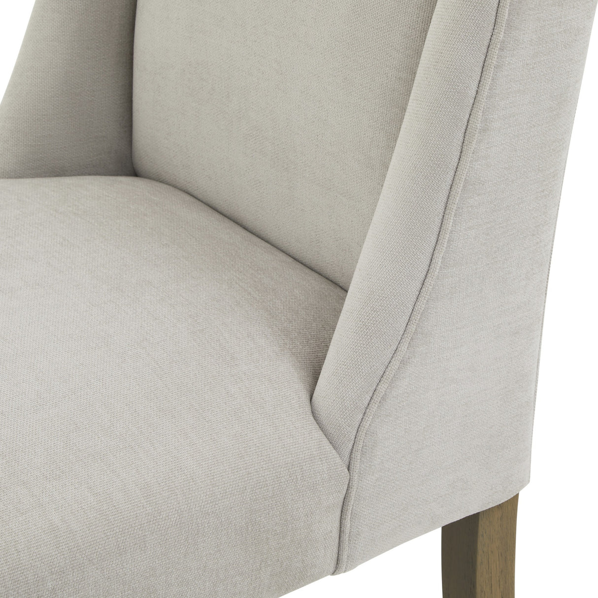 Close-up of the Hill Interiors Braxdon Upholstered Dining Chair in grey fabric, showing the padded seat, curved backrest and exposed wooden leg.