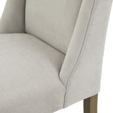Close-up of the Hill Interiors Braxdon Upholstered Dining Chair in grey fabric, showing the padded seat, curved backrest and exposed wooden leg.