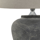 Close-up of the Hill Interiors Ferranock grey ceramic table lamp base with textured glaze finish and chrome fitting supporting a natural linen shade.