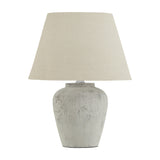 Hill Interiors Merenza table lamp with rounded antique white ceramic base and tapered natural linen shade, shown on a plain white background.