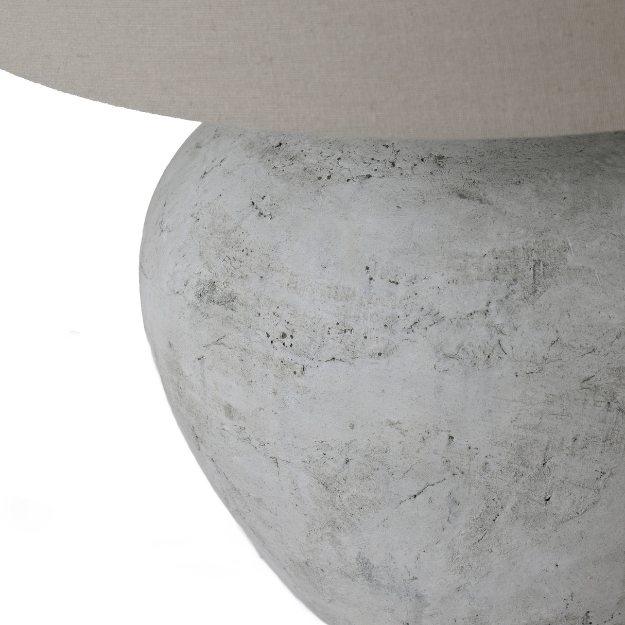 Close-up of the Hill Interiors Merenza ceramic table lamp base, showing its rounded antique white glazed form beneath a natural linen shade.