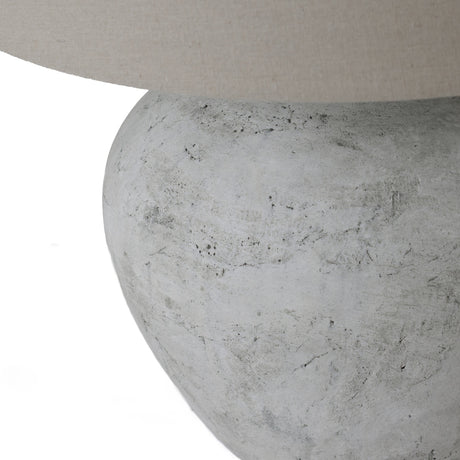 Close-up of the Hill Interiors Merenza ceramic table lamp base, showing its rounded antique white glazed form beneath a natural linen shade.