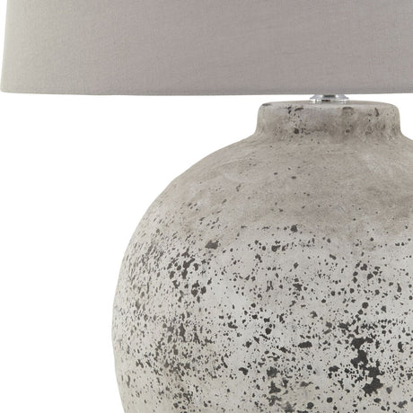 Hill Interiors Glavendor large ceramic table lamp with rounded beige stone-textured base and grey drum shade, shown against a plain white background.