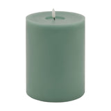 Hill Interiors Melt Effect LED wax pillar candle in muted green with flickering flame tip and softly uneven top, shown on a plain white background.