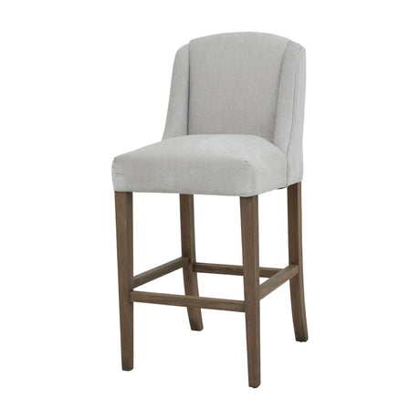 Hill Interiors Braxdon Wooden Bar Stool in grey upholstery with a curved wingback and wood legs joined by stretchers, shown on a plain white background.