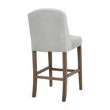 Rear view of the Hill Interiors Braxdon wooden bar stool in soft grey upholstery with a shaped back and four tapered wood legs, on a white background.