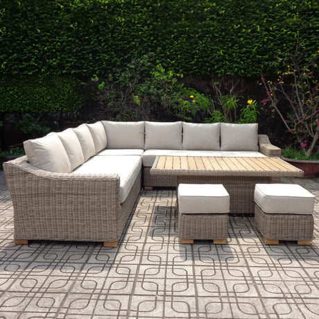 Hill Interiors large beige outdoor corner sofa set with cushioned L-shaped seating, timber-topped riser table and two matching stools on a patio.