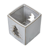 Hill Interiors white ceramic square tealight holder with pierced tree cut-outs on each side, shown from above on a plain white background.