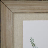 Close-up of the Hill Interiors Delicate Fern Print corner, showing the washed pale brown wood frame, linen-style mount and soft green fern detail.