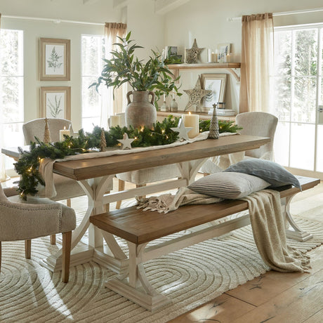 Hill Interiors large wicker five-point star decoration in warm brown, styled on a dining table with pine garland, candles and festive decor.