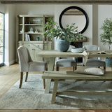 Hill Interiors grey ceramic water pot planter with olive foliage on a rustic dining table, styled with upholstered chairs, bench and round black mirror.