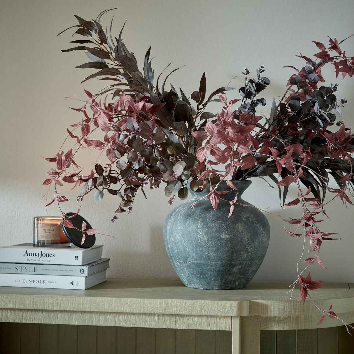 Hill Interiors Ceramic Vase 30cm in grey, rounded form filled with burgundy foliage and eucalyptus, styled on a wooden console with books and a candle.