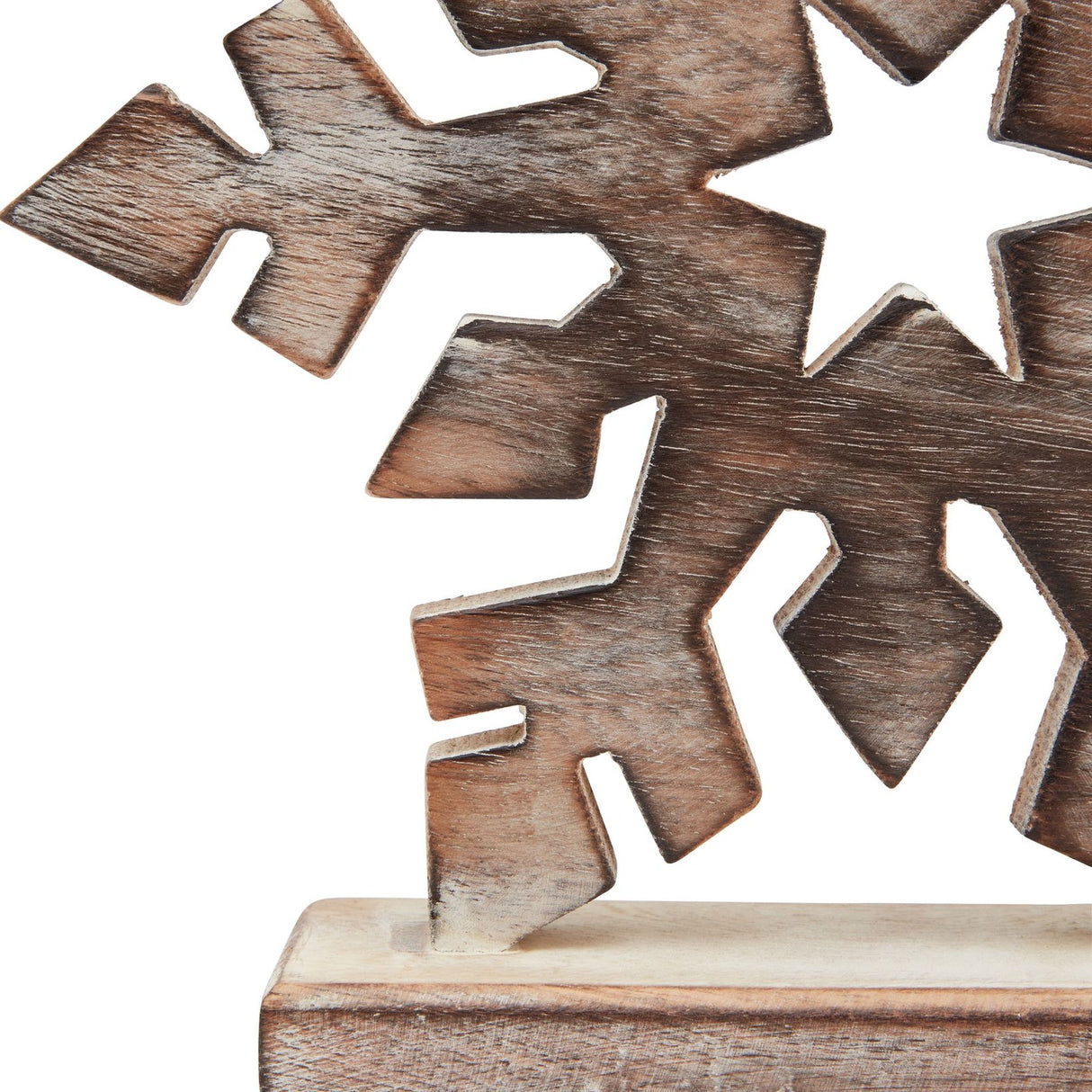 Close-up of Hill Interiors white wash wooden snowflake decoration in brown, showing carved six-point detail, visible grain, and wooden base.