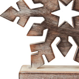 Close-up of Hill Interiors white wash wooden snowflake decoration in brown, showing carved six-point detail, visible grain, and wooden base.