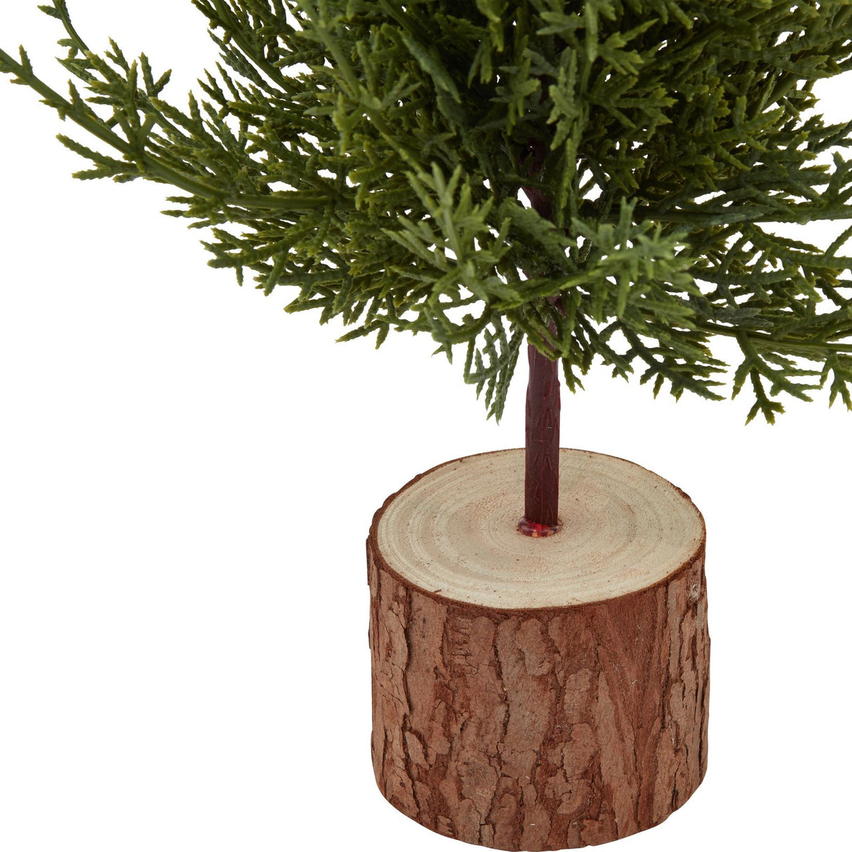 Close-up of Hill Interiors Small Green Fir Tree base, showing the plastic green foliage set into a natural wood log stand on a white background.