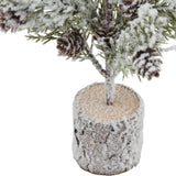 Close-up of Hill Interiors Small Snowy Fir Tree in Wood Log showing the frosted branches with pinecones rising from a snow-dusted brown log base.