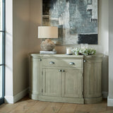 Hill Interiors winter wreath with lambs ear and white wax flower styled on a wooden sideboard beside pillar candles, a stone lamp and abstract wall art.