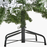 Close-up of the black metal folding stand and lower snow-dusted branches of the Hill Interiors Extra Large Snowy Spruce Tree on a white background.