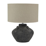Hill Interiors Ferranock Lekanis table lamp with a rounded grey ceramic base and oatmeal linen drum shade, shown on a plain white background.