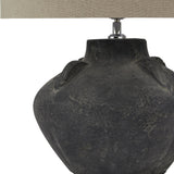Close-up of the Hill Interiors Ferranock Lekanis ceramic table lamp showing its rounded grey chalky-glazed body and oatmeal linen drum shade base.