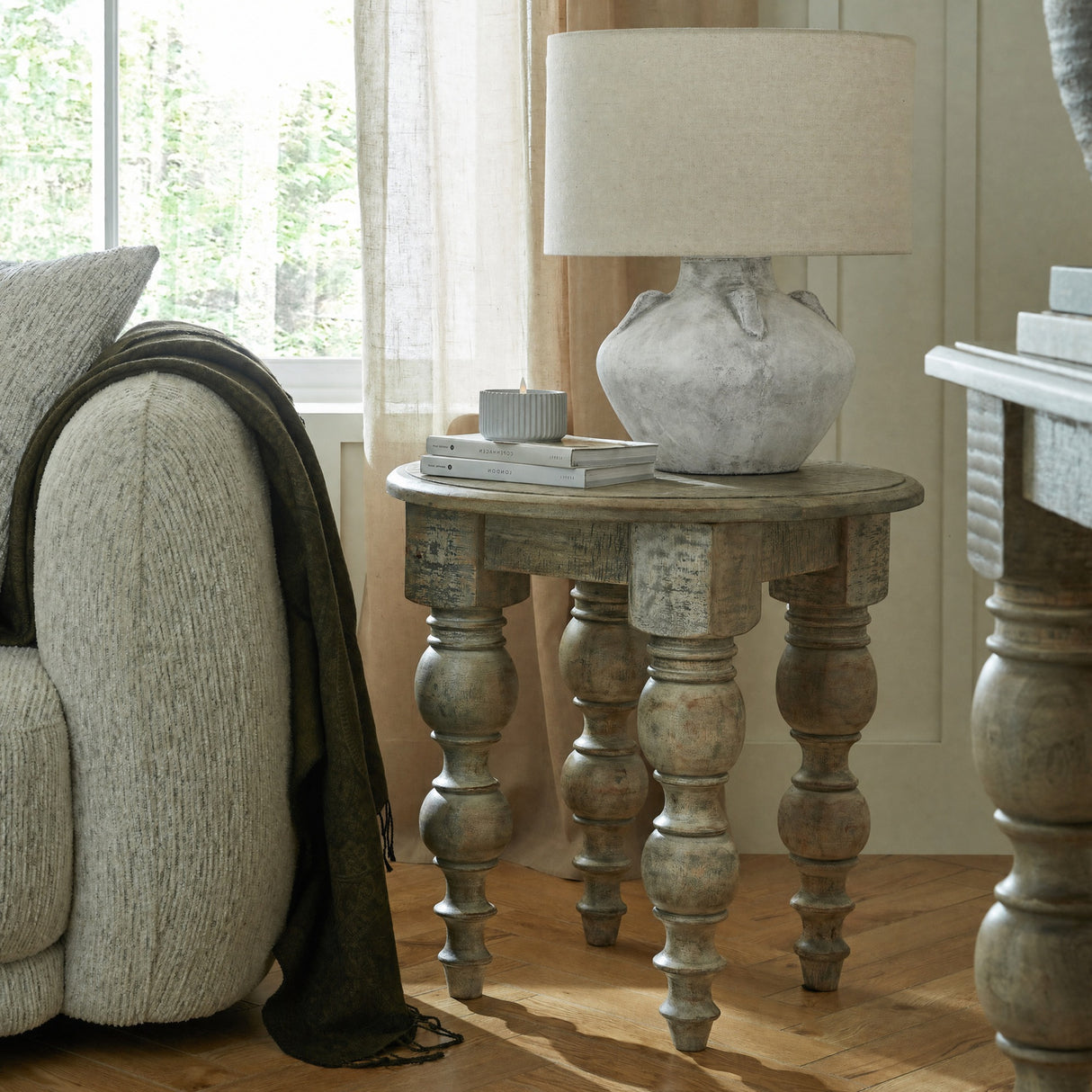 Hill Interiors Elvessa stone lekanis table lamp in beige ceramic with linen drum shade, styled on a turned-leg wooden side table beside a window.