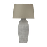 Hill Interiors Elvessa table lamp with a tall ridged grey-beige ceramic urn base and a tapered oatmeal linen drum shade, on a white background.