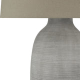 Close-up of the Hill Interiors Elvessa ceramic table lamp base, showing its ribbed grey stone-effect texture and beige linen shade edge.