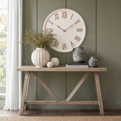 Hill Interiors Large Rustic Beaded Frame Wall Clock in white with gold Roman numerals, mounted above a wooden console table styled with vases.