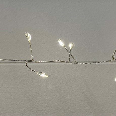 Hill Interiors 7.2m plug-in LED cluster micro string lights glowing warm white along a slim wire against a plain pale wall.