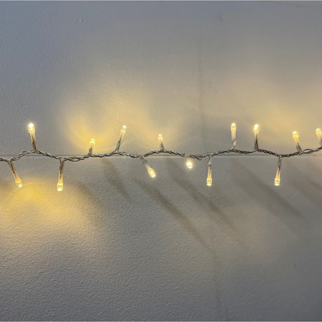 Hill Interiors 13.6m plug in LED string light glowing warm white along a slim clear cable against a plain white wall.