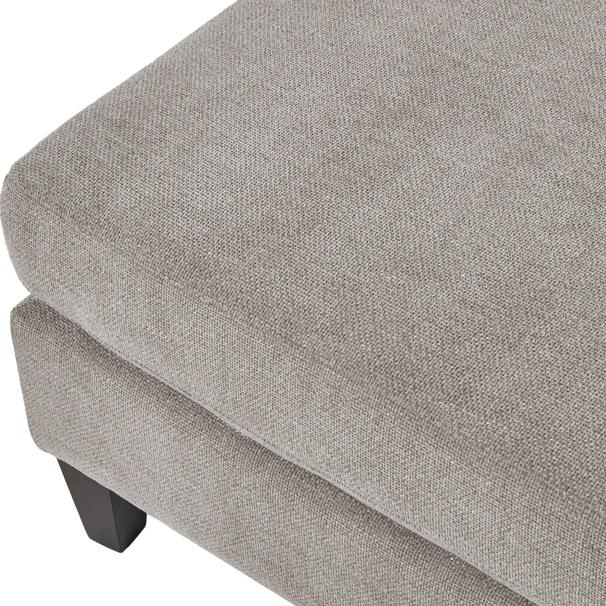Close-up of the Hill Interiors Upholstered Ottoman Foot Stool in beige, showing the woven fabric top, cushioned edge and dark wooden leg.