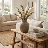 Hill Interiors Large Ceramic Vase in grey with ribbed body, holding dried eucalyptus and pampas on a wooden bench in a neutral linen living room.