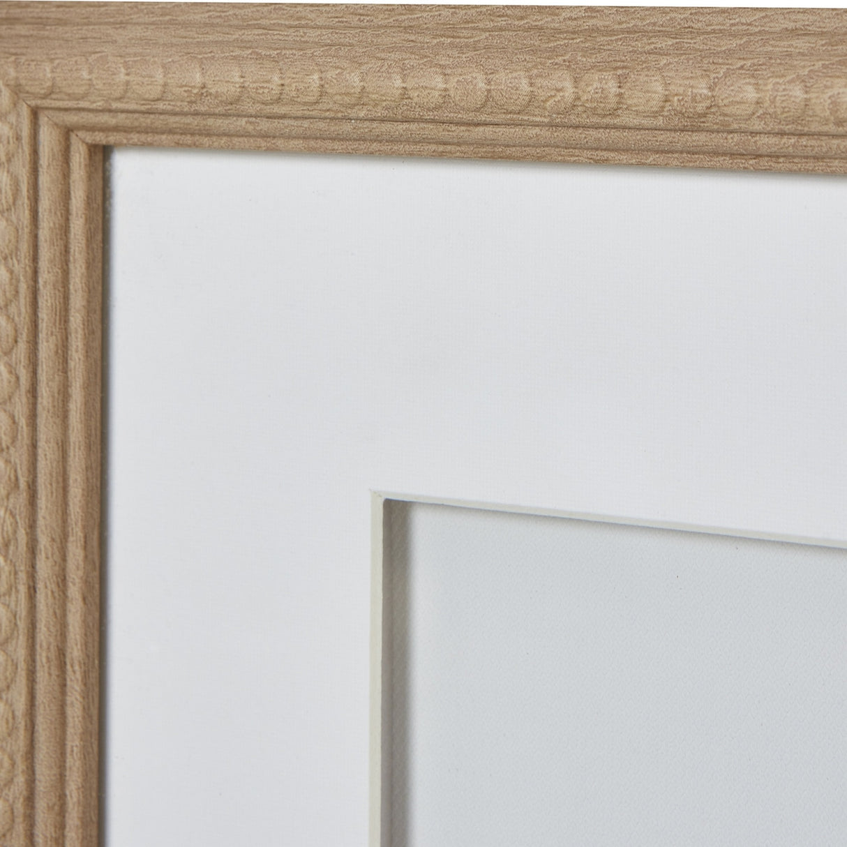 Close-up of the Hill Interiors Reef Coral framed wall art showing the light wood beaded border frame, white mount and glass front.