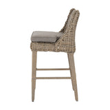 Side view of Hill Interiors Metal Outdoor Bar Stool in beige with woven frame, cushioned seat and footrest, shown on a plain white background.