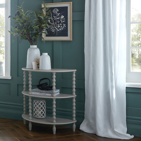 Hill Interiors Half Moon 3 Tier Side Table in grey wood, styled with vases and books against a green panelled wall beside a curtained window.