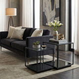 Hill Interiors Harweld black framed glass side tables set of two, nested in a modern living room beside a dark grey velvet sofa.