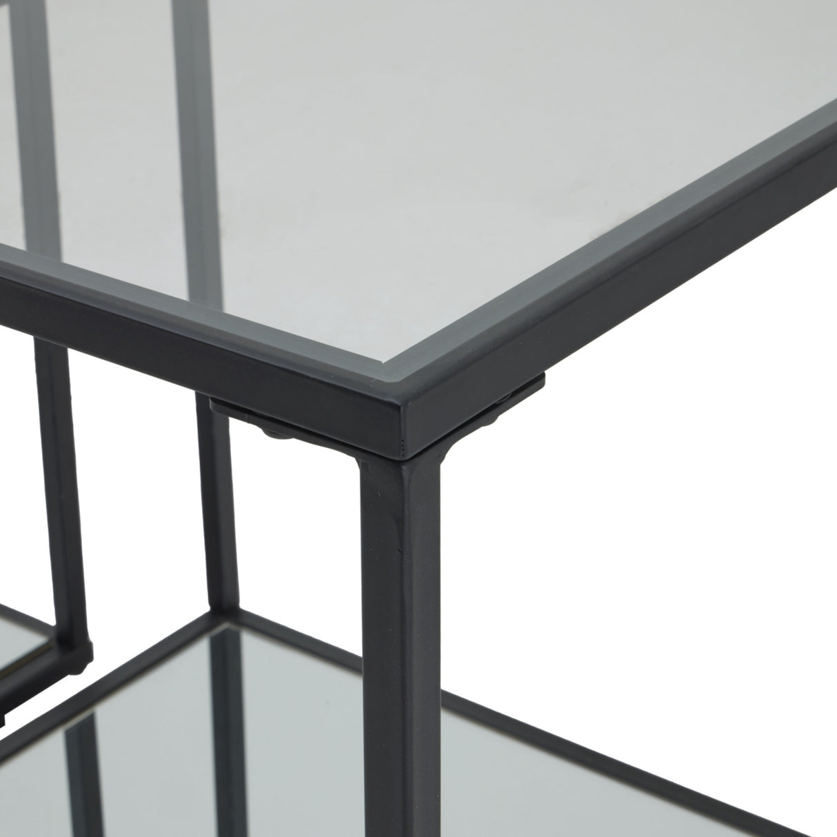 Close-up of the Hill Interiors Harweld side tables showing the slim black metal frame corners and clear glass tops of the nesting pair.